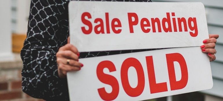 Woman holding a sign SOLD and Sale Pending