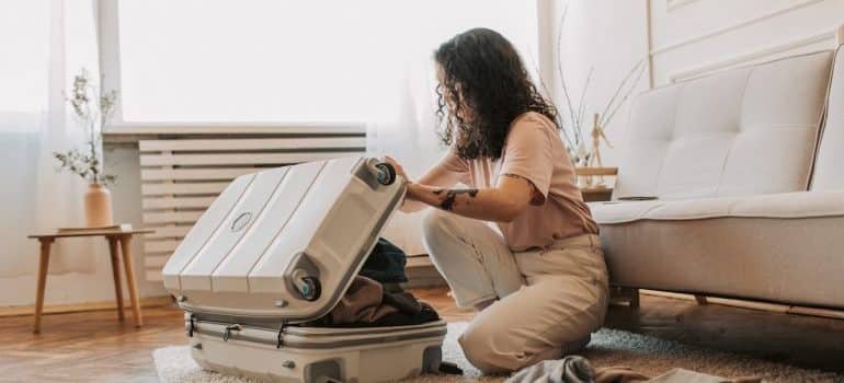 A woman packing her suitcase for a DIY move.