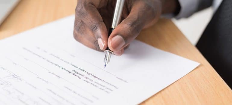 A hand signing some documents.